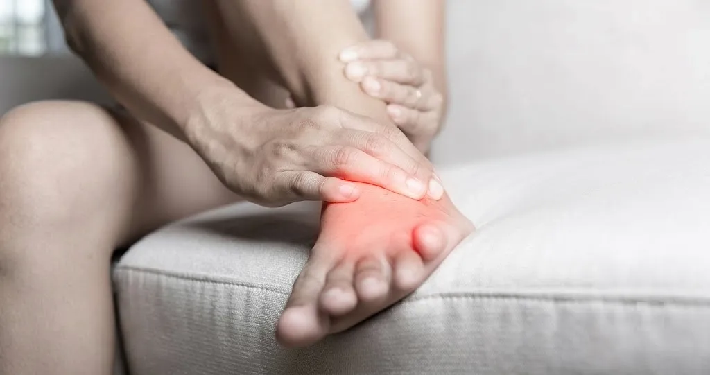 A person touching the outer side of their foot with a red highlight, demonstrating localized pain and swelling—one of the key symptoms of peroneal tendonitis.